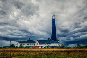 Bolivar Point Lighthouse — The tall, dark tower of Bolivar Point Lighthouse rises above the keepers' houses beneath a sky churning with storm