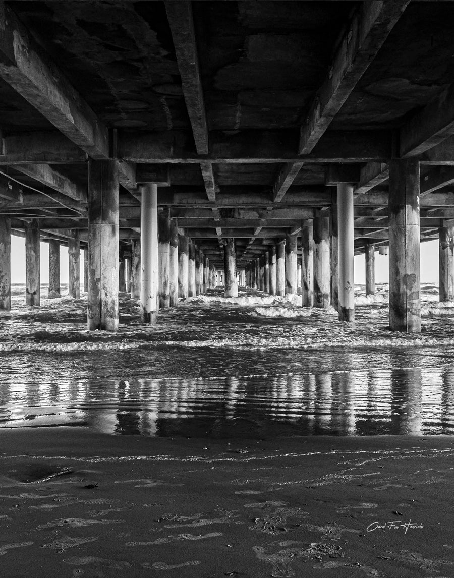 Under Pleasure Pier — Beneath the boards of Galveston's Pleasure Pier, rows of heavy pilings recede into the distance